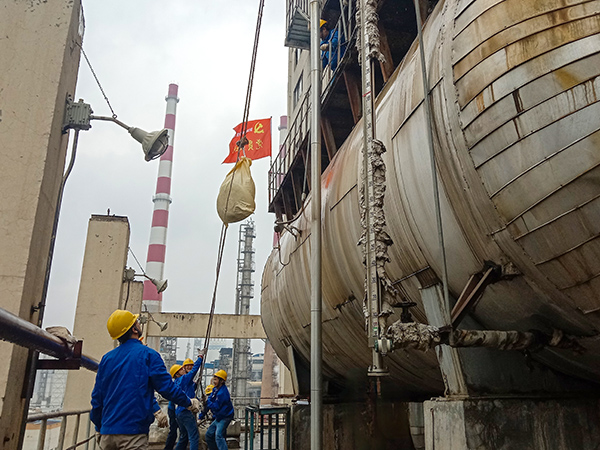 5月10日中午，在動(dòng)力車間三期工藝除氧器地面，黨員突擊隊(duì)隊(duì)員用滑輪往工藝除氧器平臺(tái)運(yùn)送鋼絲網(wǎng)，用以纏繞新填料.jpg