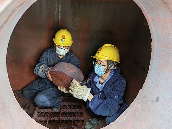 5月11日，動(dòng)力車間三期工藝除氧器內(nèi)部，黨員突擊隊(duì)隊(duì)員劉瑞斌和李震正在清理舊填料.jpg